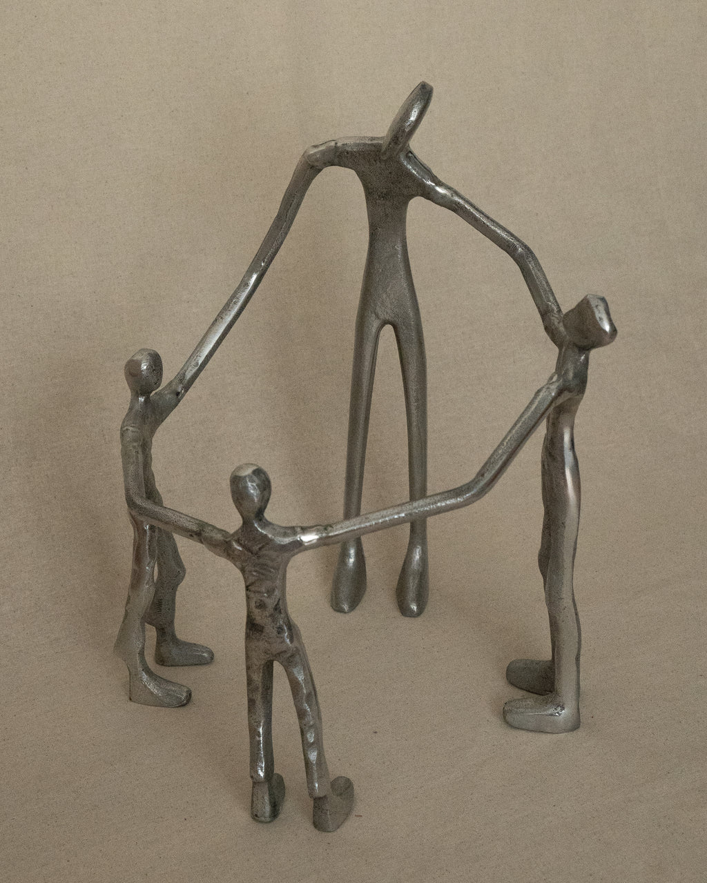 4 aluminum humans holding hands in a circle