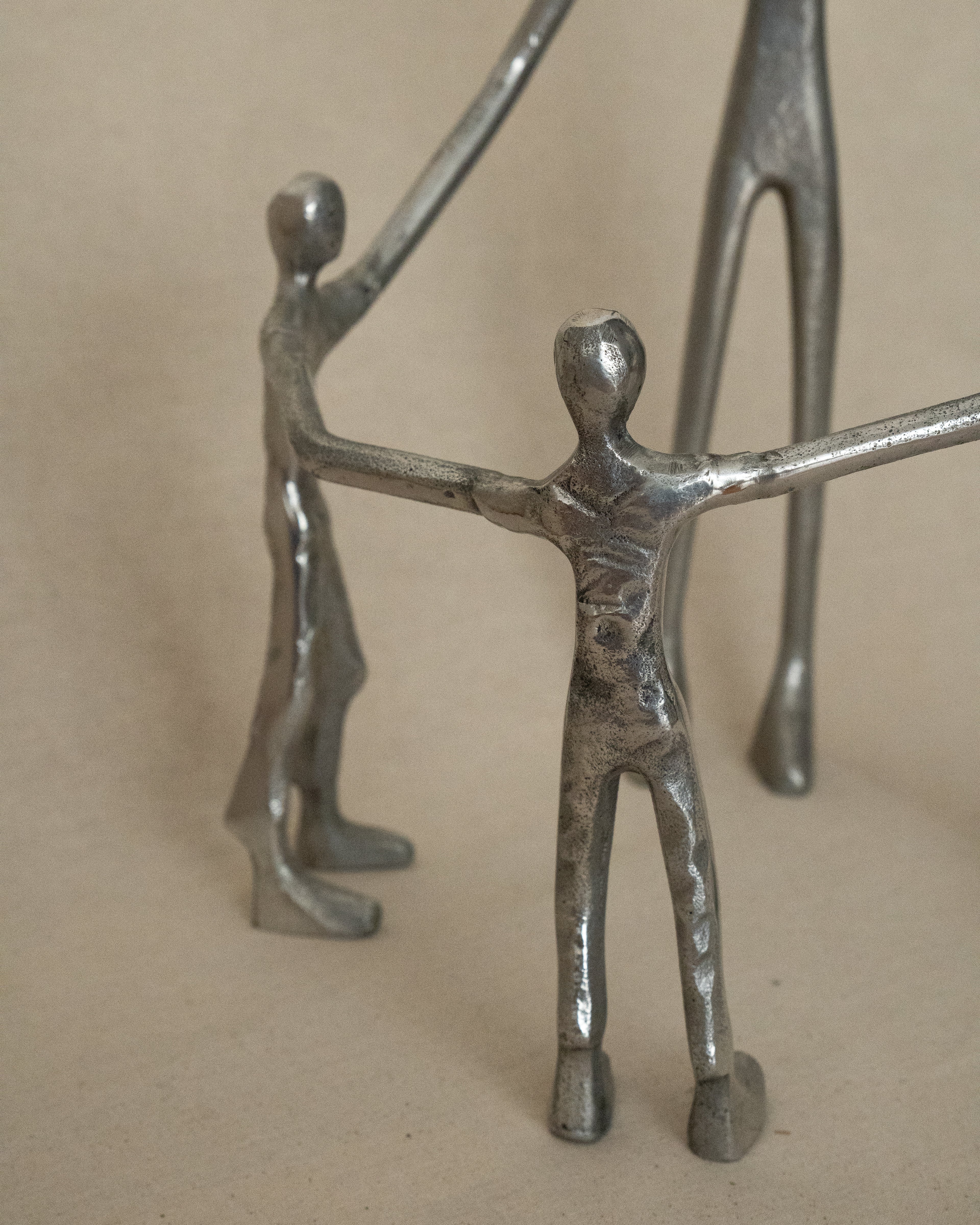 4 aluminum humans holding hands in a circle