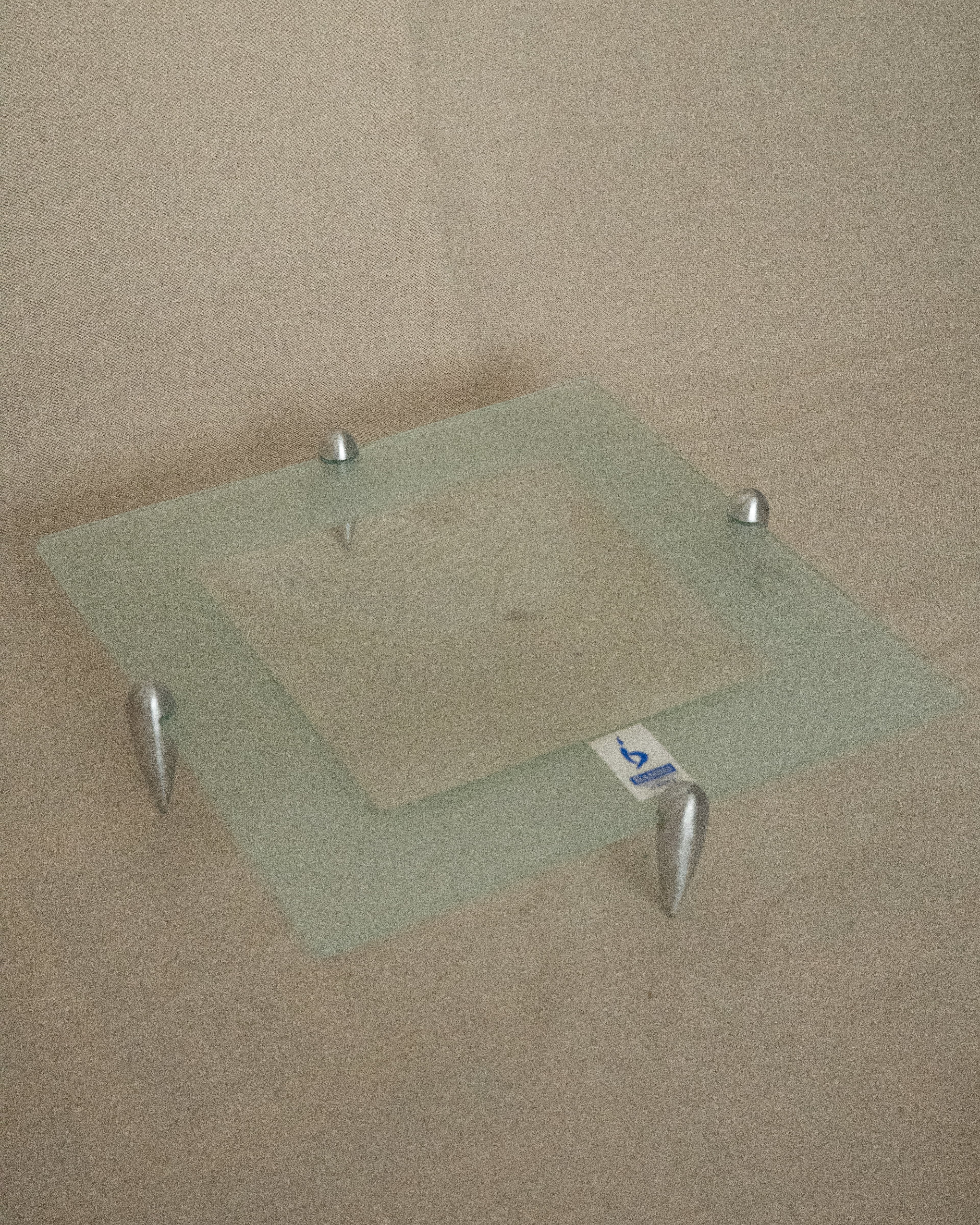 Glass square dish raised by atomic silver feet