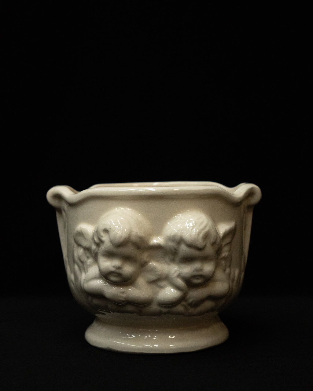 White ceramic pot featuring two pairs of cherubs