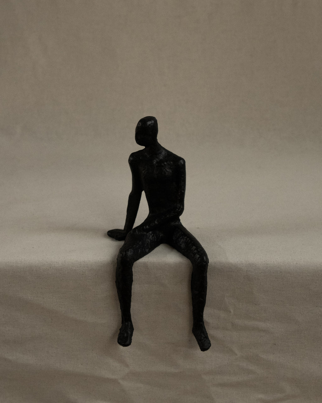 Black metal edge-sitting human sculpture