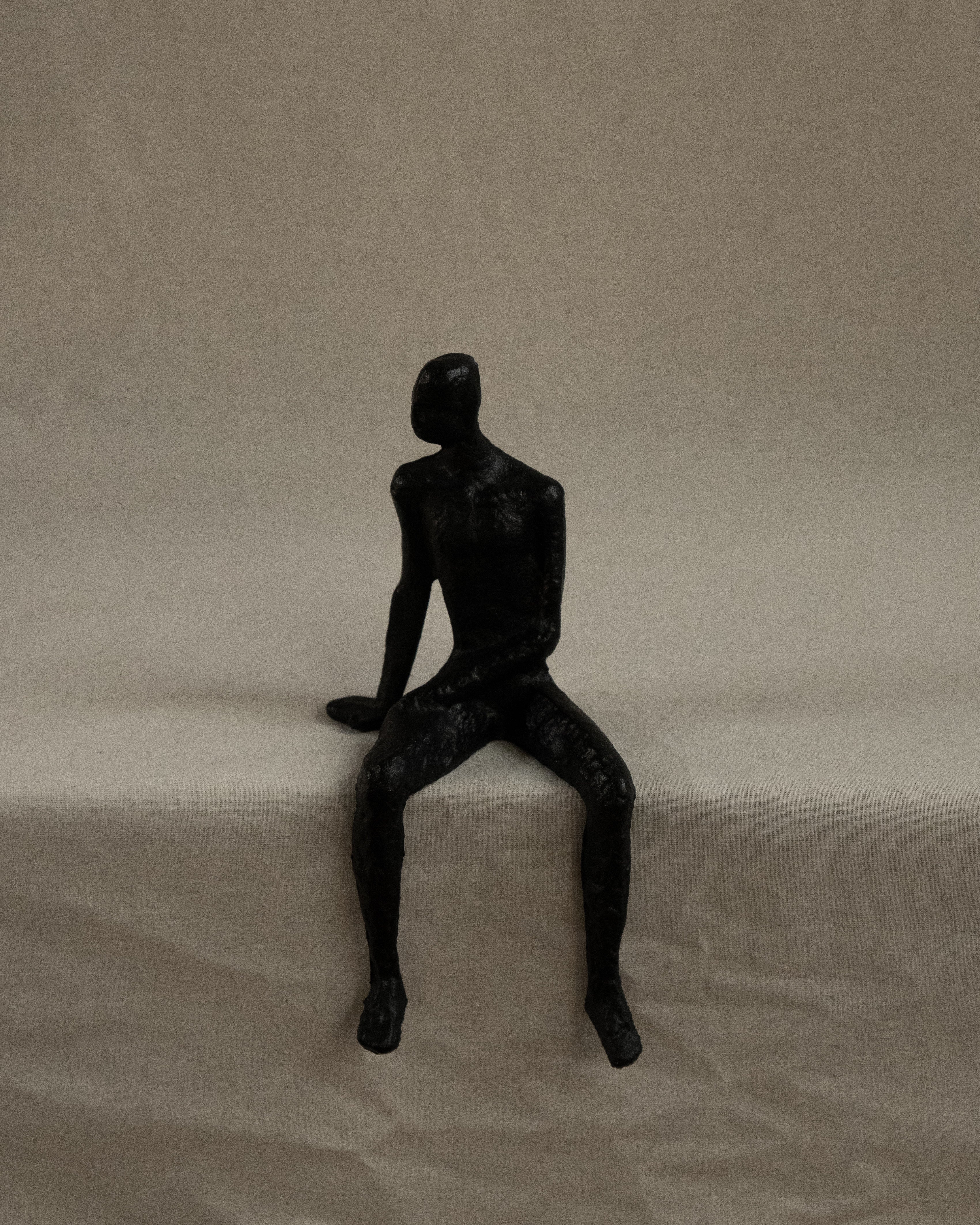 Black metal edge-sitting human sculpture