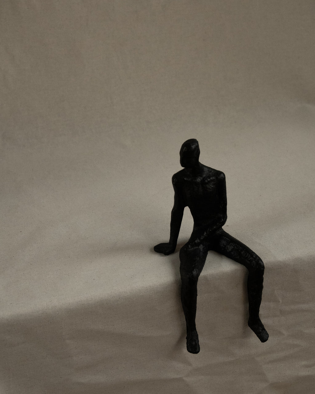 Black metal edge-sitting human sculpture