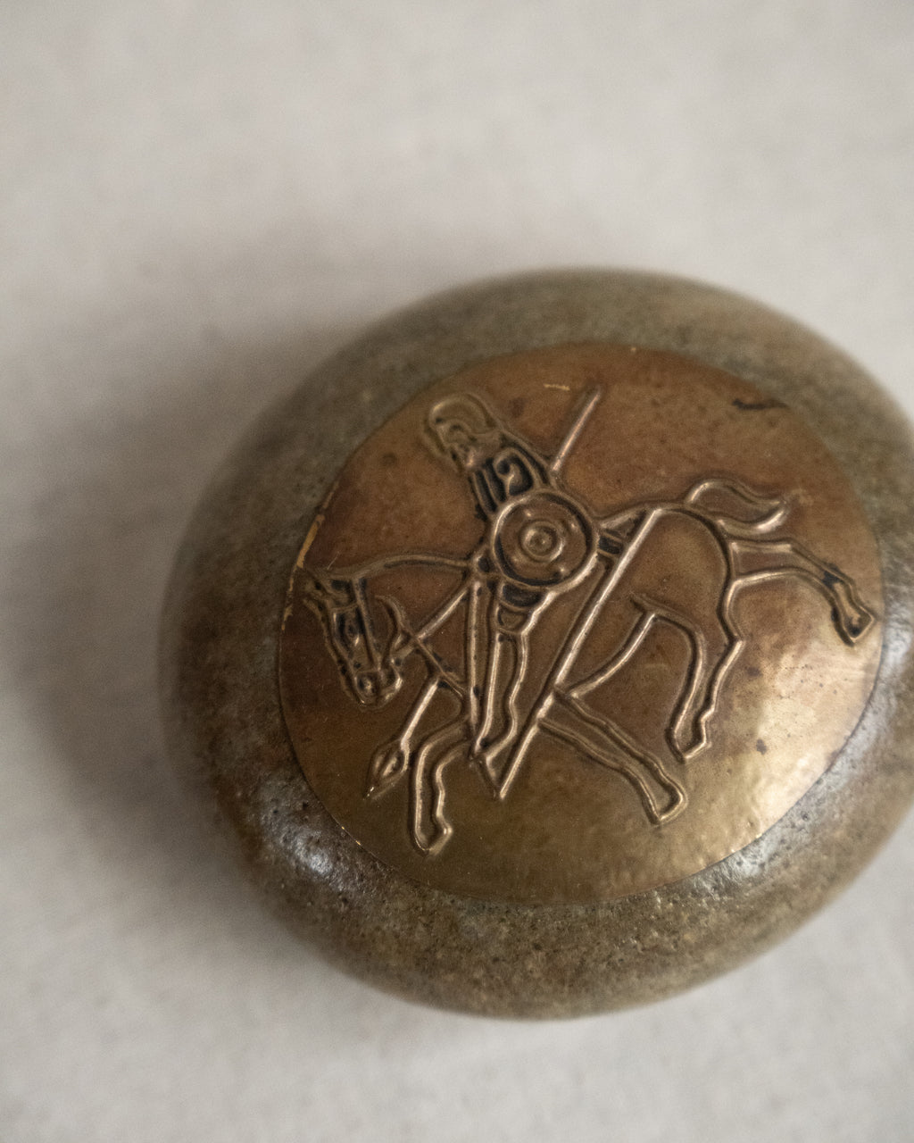 Embossed metal art on stone featuring a knight on a horse