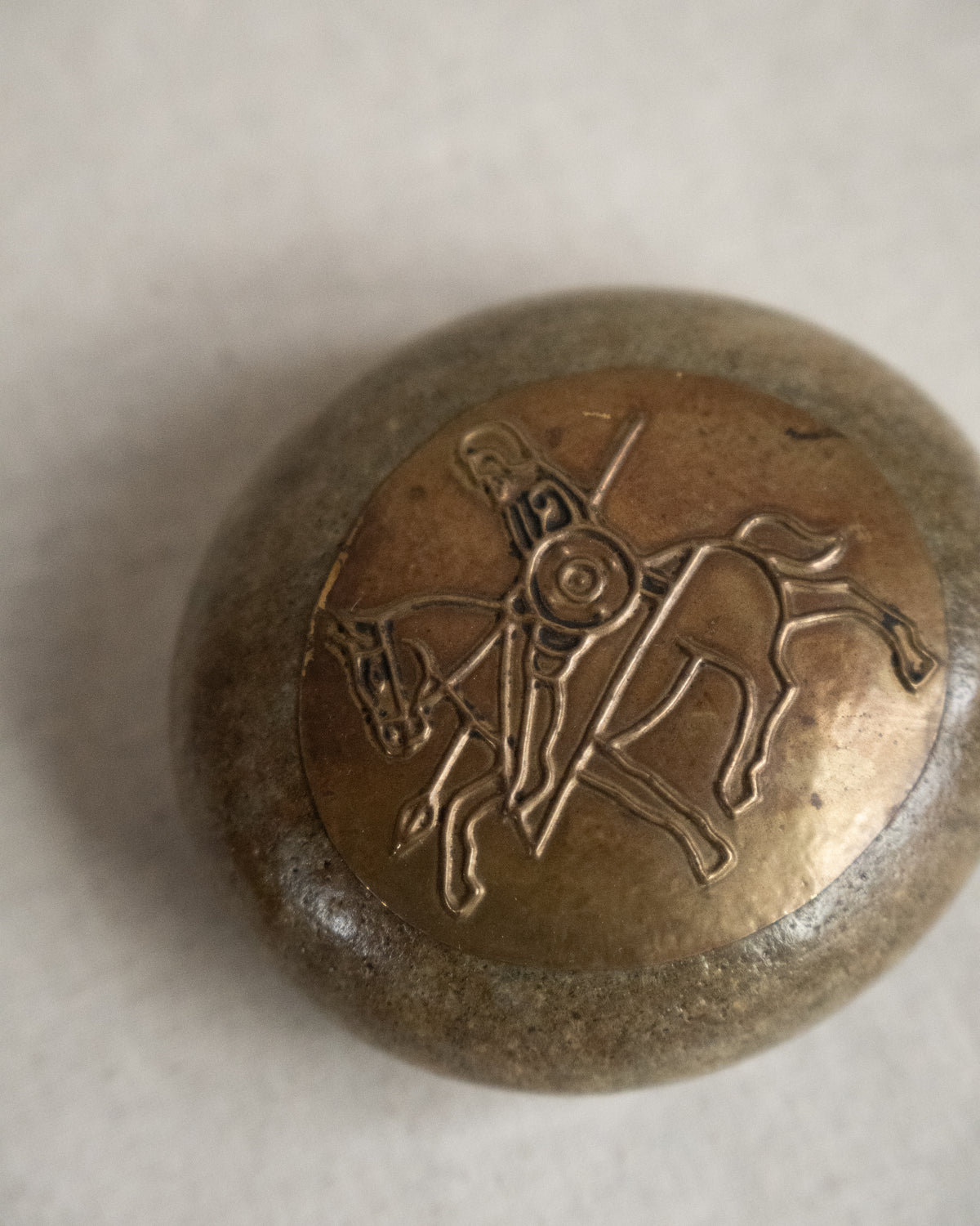 Embossed metal art on stone featuring a knight on a horse