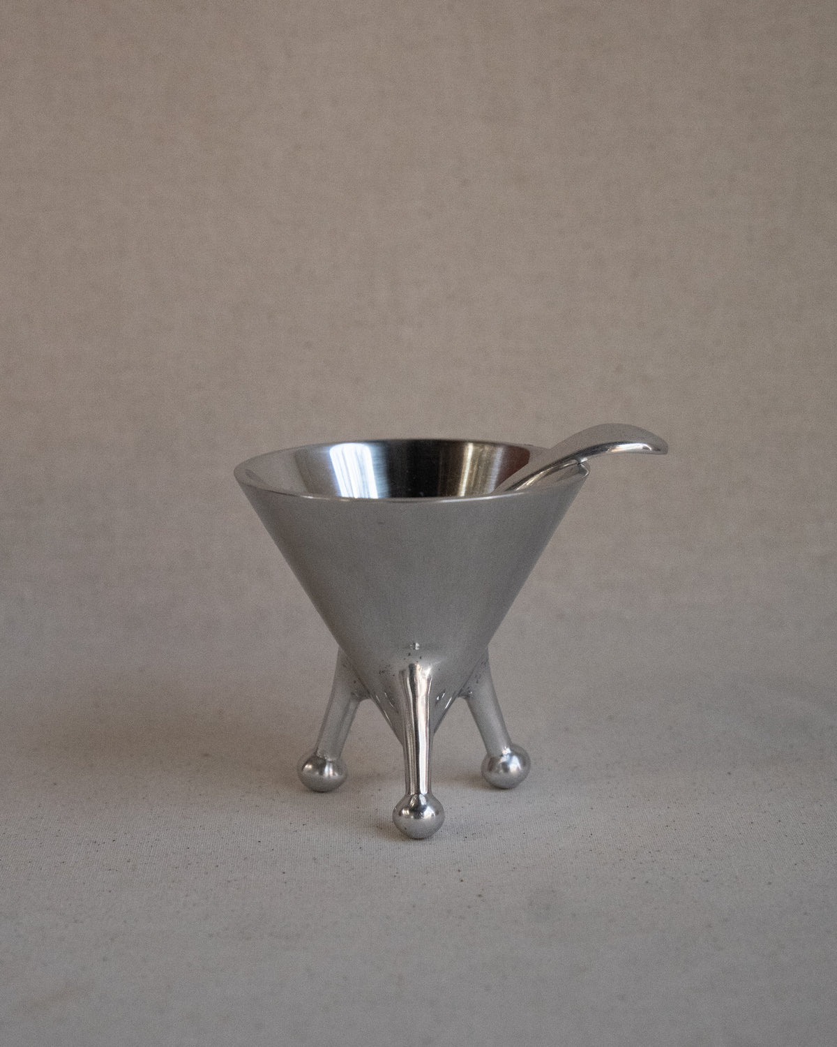 Metal sugar bowl with spoon on raised atomic feet