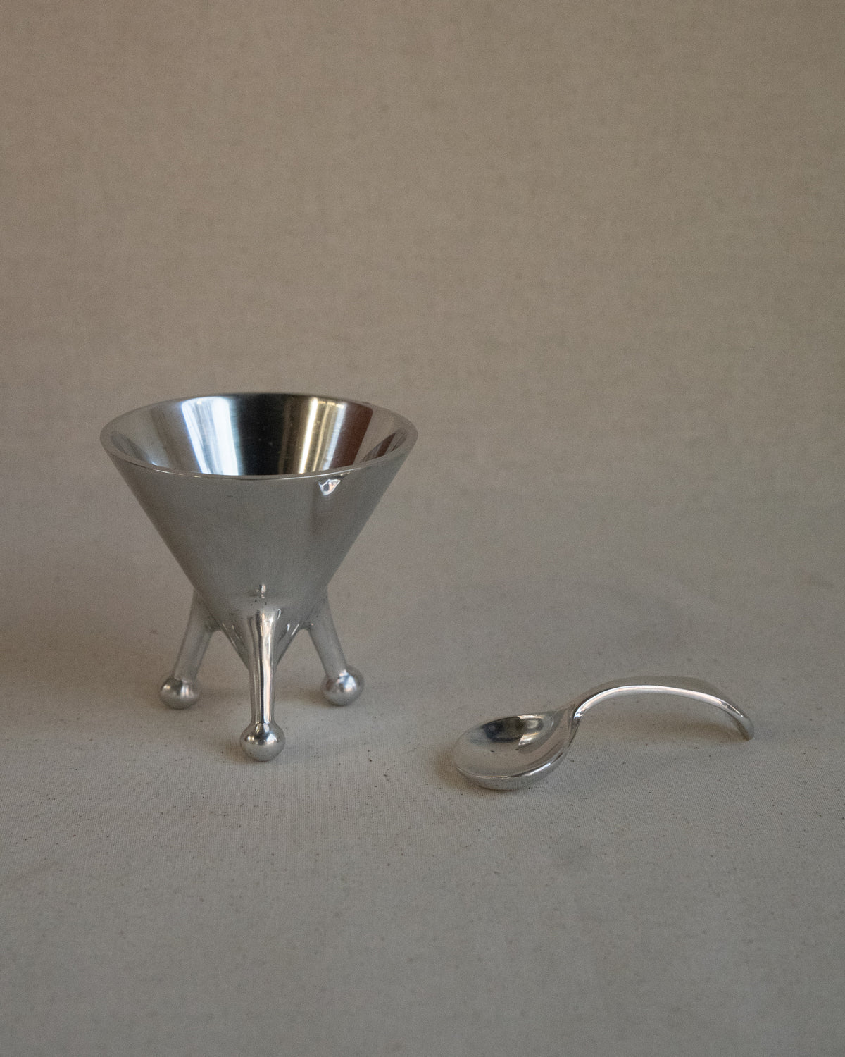 Metal sugar bowl with spoon on raised atomic feet
