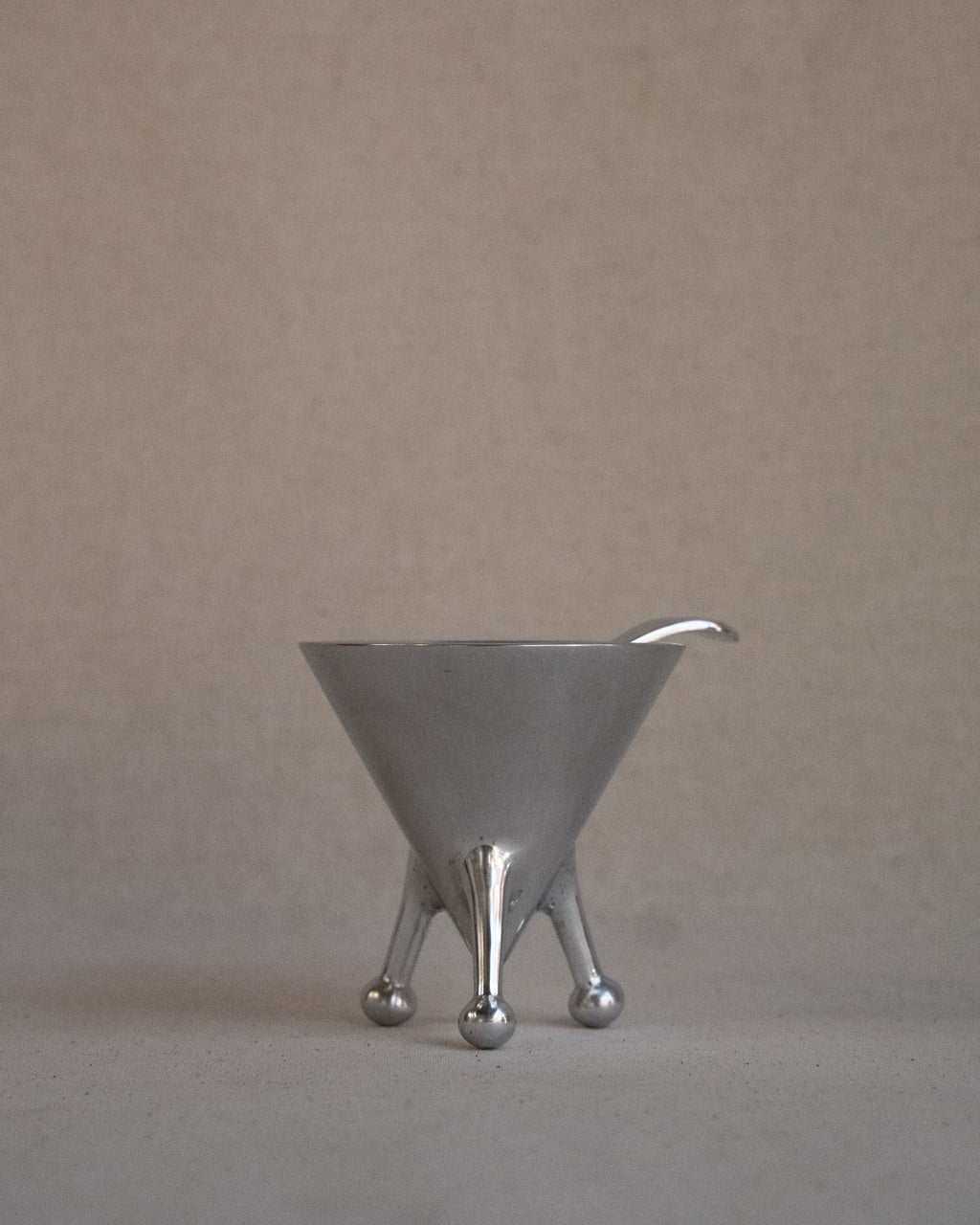 Metal sugar bowl with spoon on raised atomic feet
