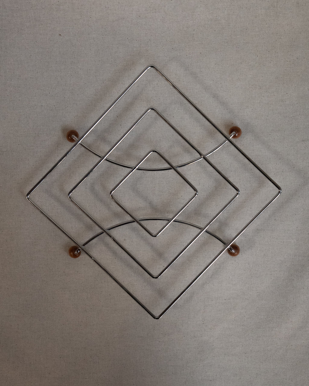 Metal trivet with wooden ball feet