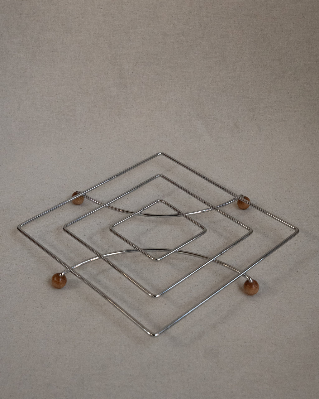 Metal trivet with wooden ball feet