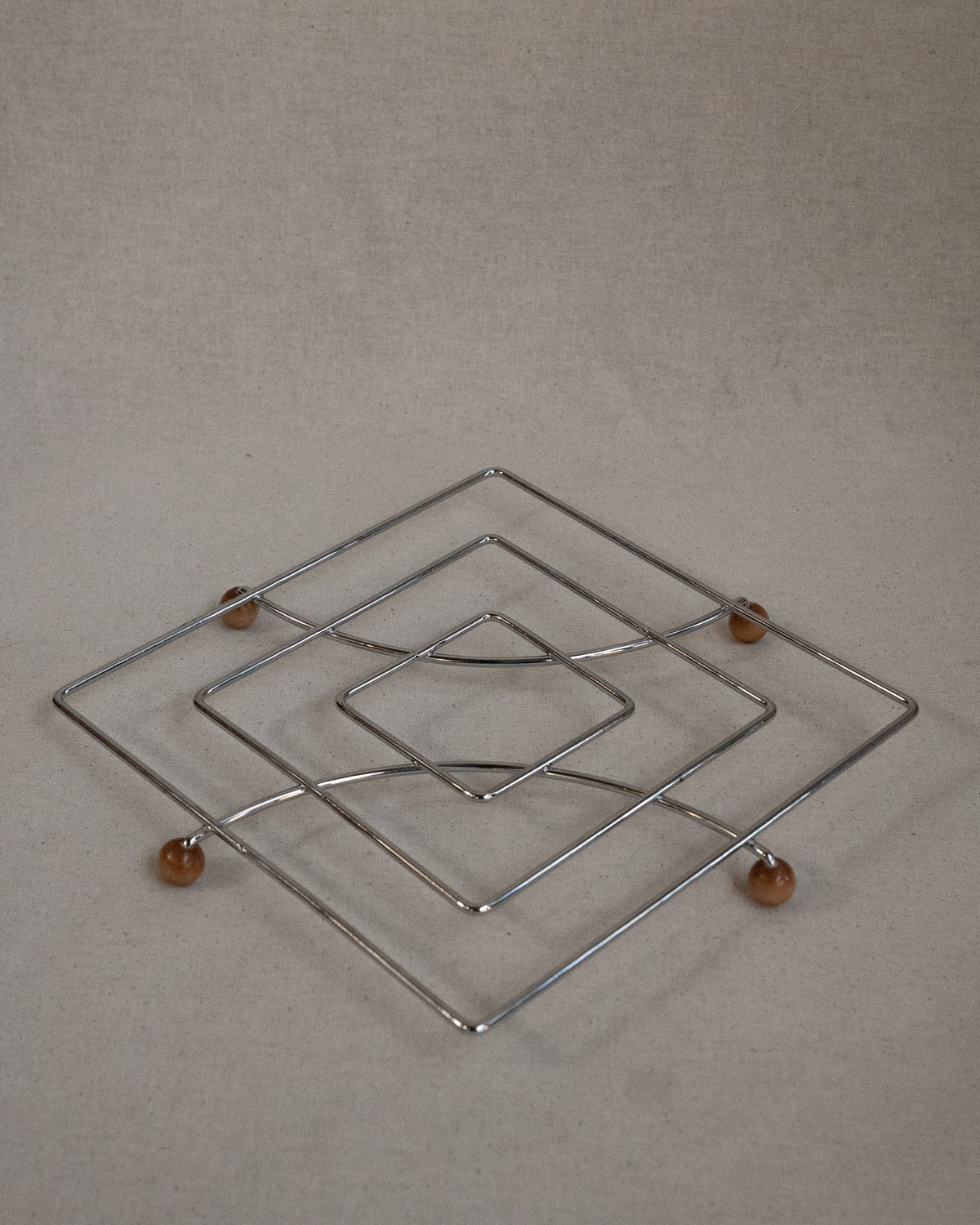 Metal trivet with wooden ball feet