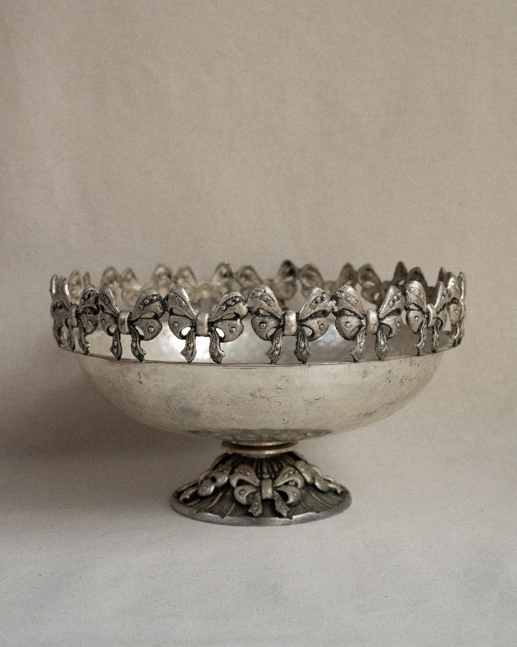 Metal raised bowl with bow details in silver-brass finish