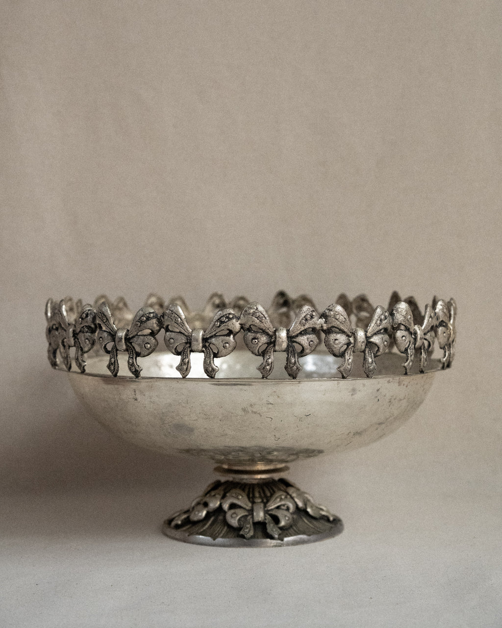 Metal raised bowl with bow details in silver-brass finish
