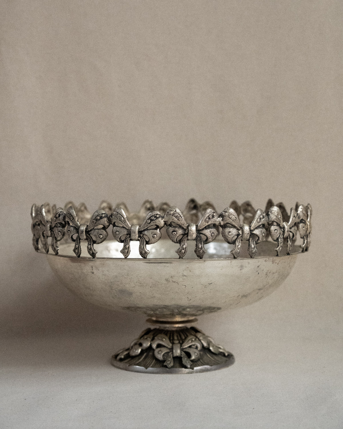 Metal raised bowl with bow details in silver-brass finish