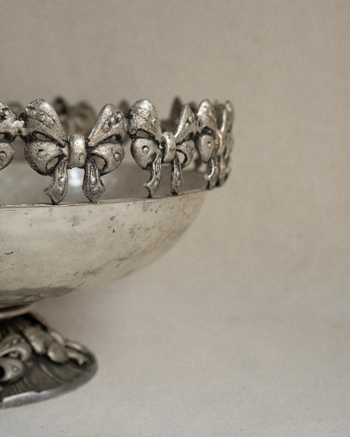 Metal raised bowl with bow details in silver-brass finish