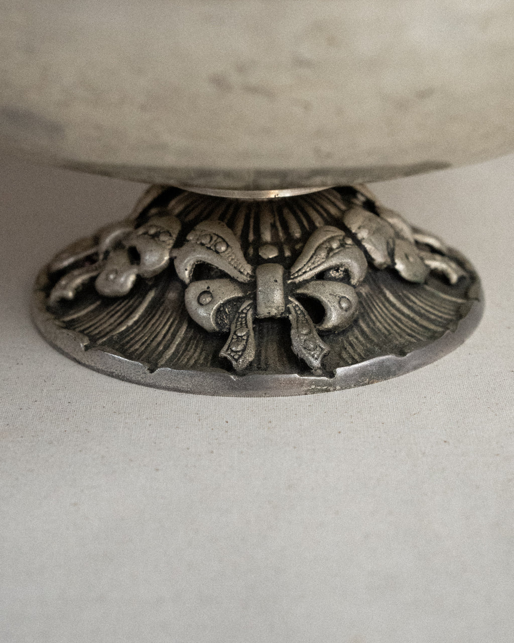 Metal raised bowl with bow details in silver-brass finish