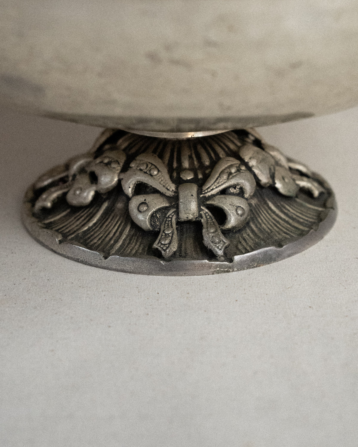 Metal raised bowl with bow details in silver-brass finish