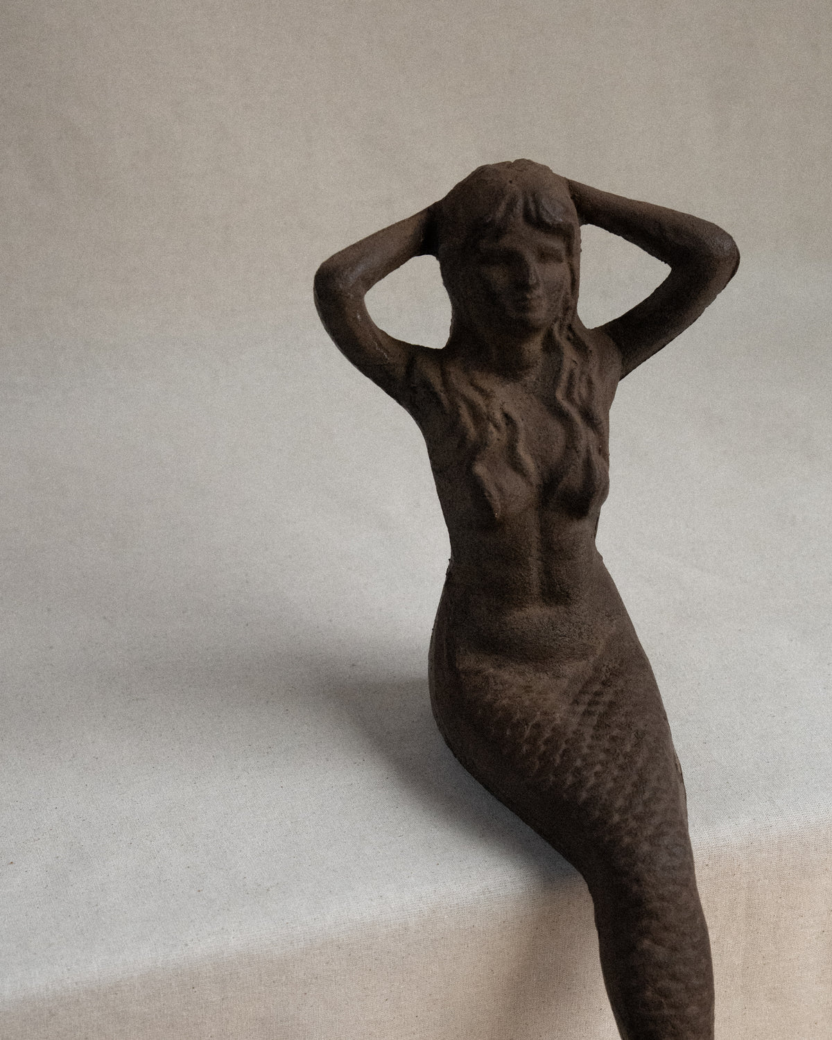 Edge-sitting cast iron mermaid sculpture