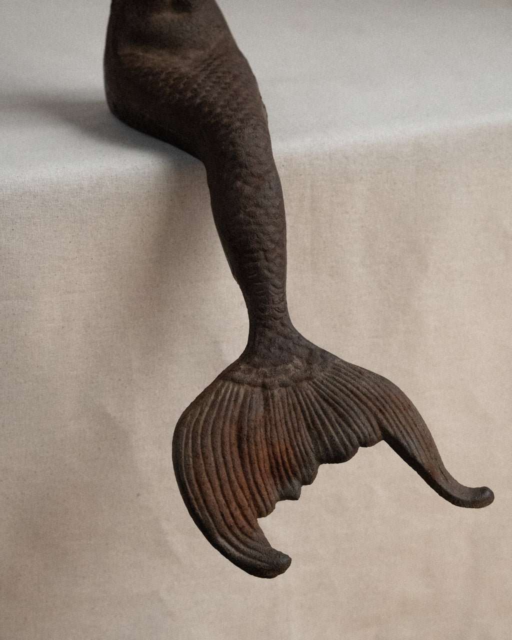 Edge-sitting cast iron mermaid sculpture