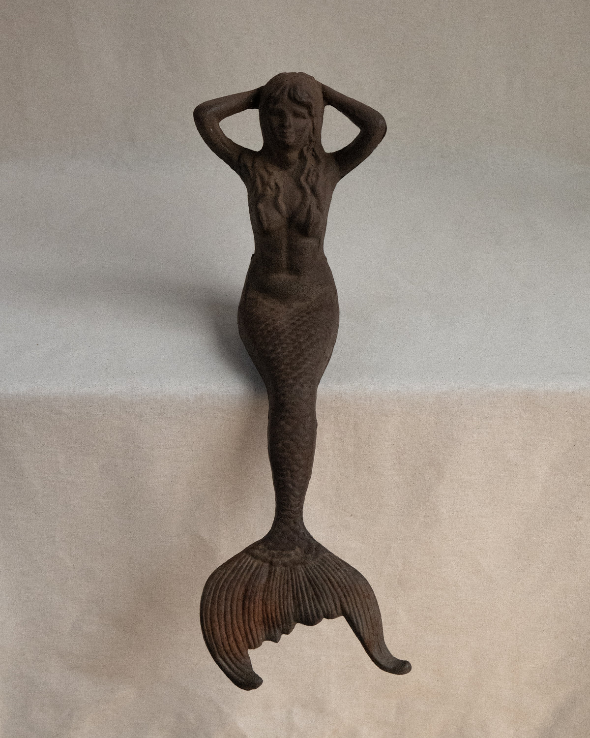 Edge-sitting cast iron mermaid sculpture