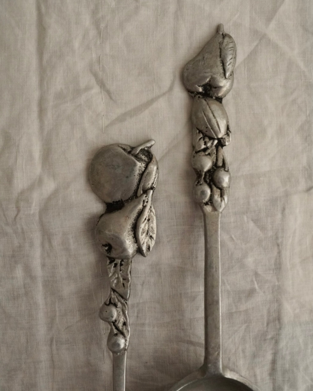 A pair of large metal serving utensils with fruit handles