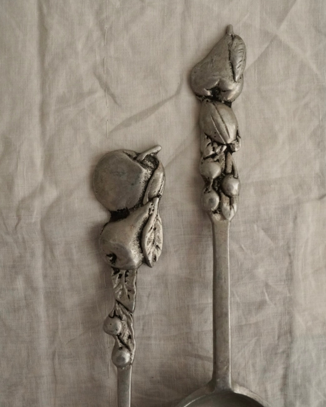 A pair of large metal serving utensils with fruit handles
