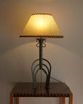 Lamp with iron base and rawhide shade with leather cross stitch edges