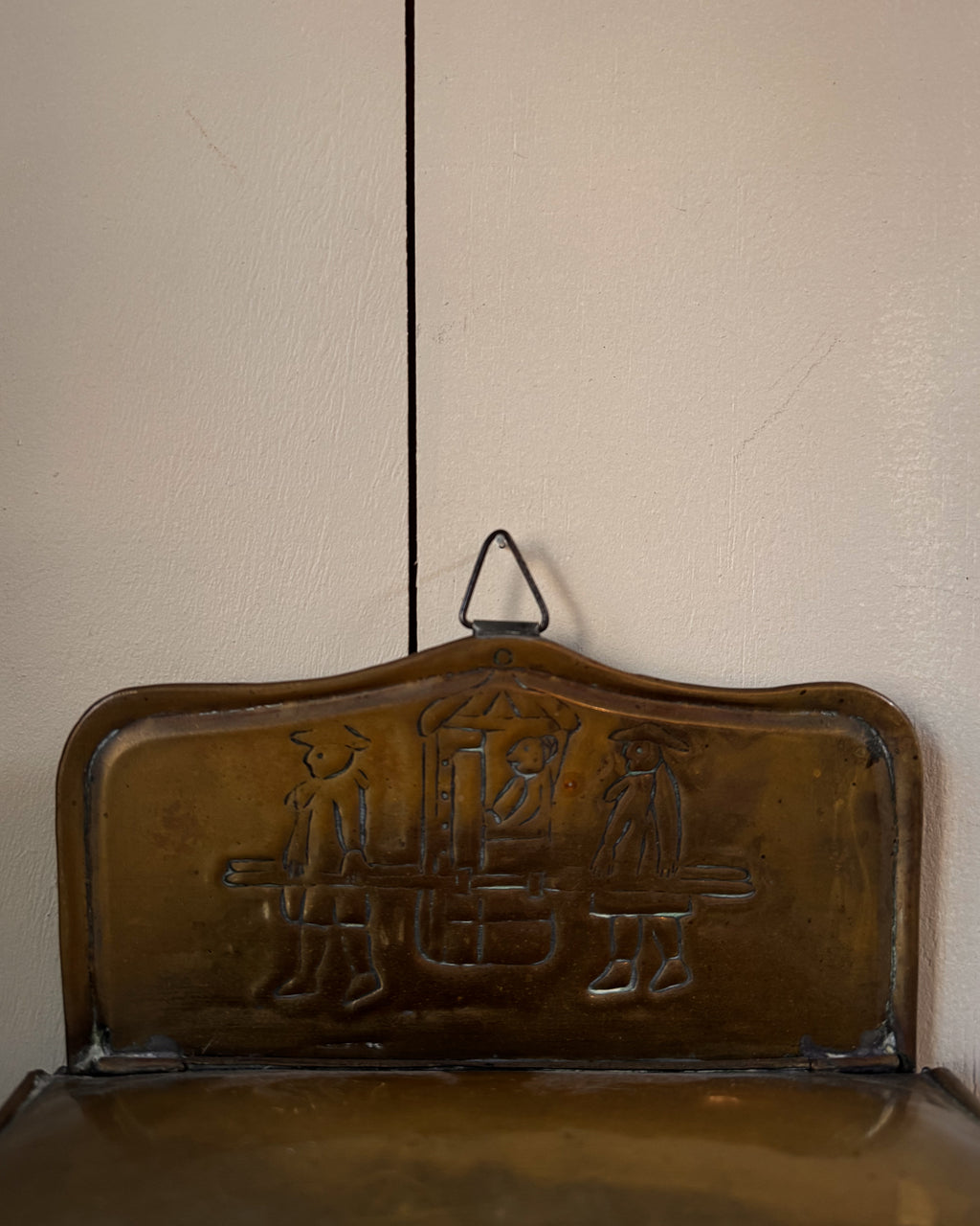 Brass wall hanging container with two individuals carrying a sedan chair