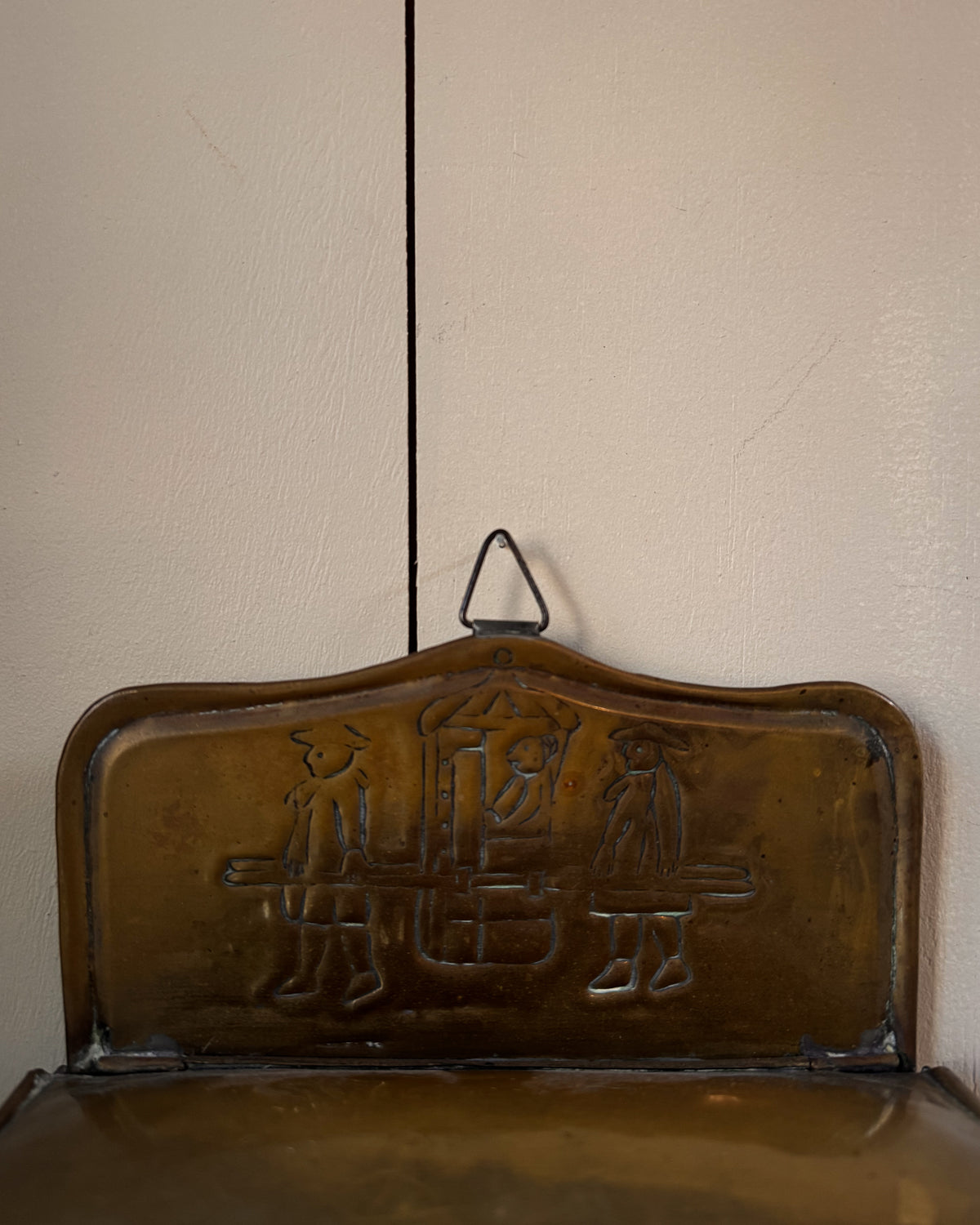 Brass wall hanging container with two individuals carrying a sedan chair