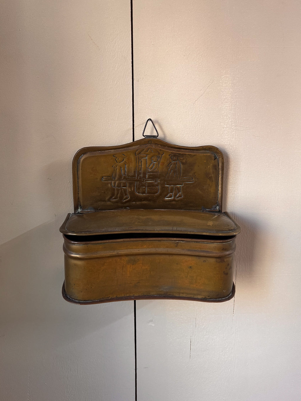 Brass wall hanging container with two individuals carrying a sedan chair