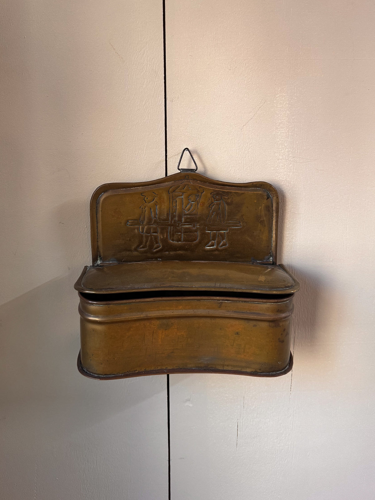 Brass wall hanging container with two individuals carrying a sedan chair