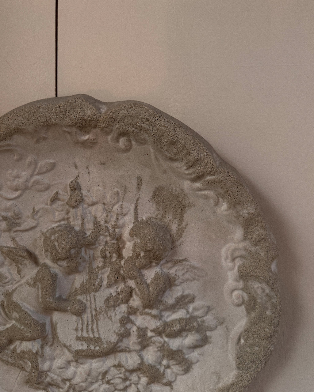 Concrete wall hanging of cherubs playing a lyre harp