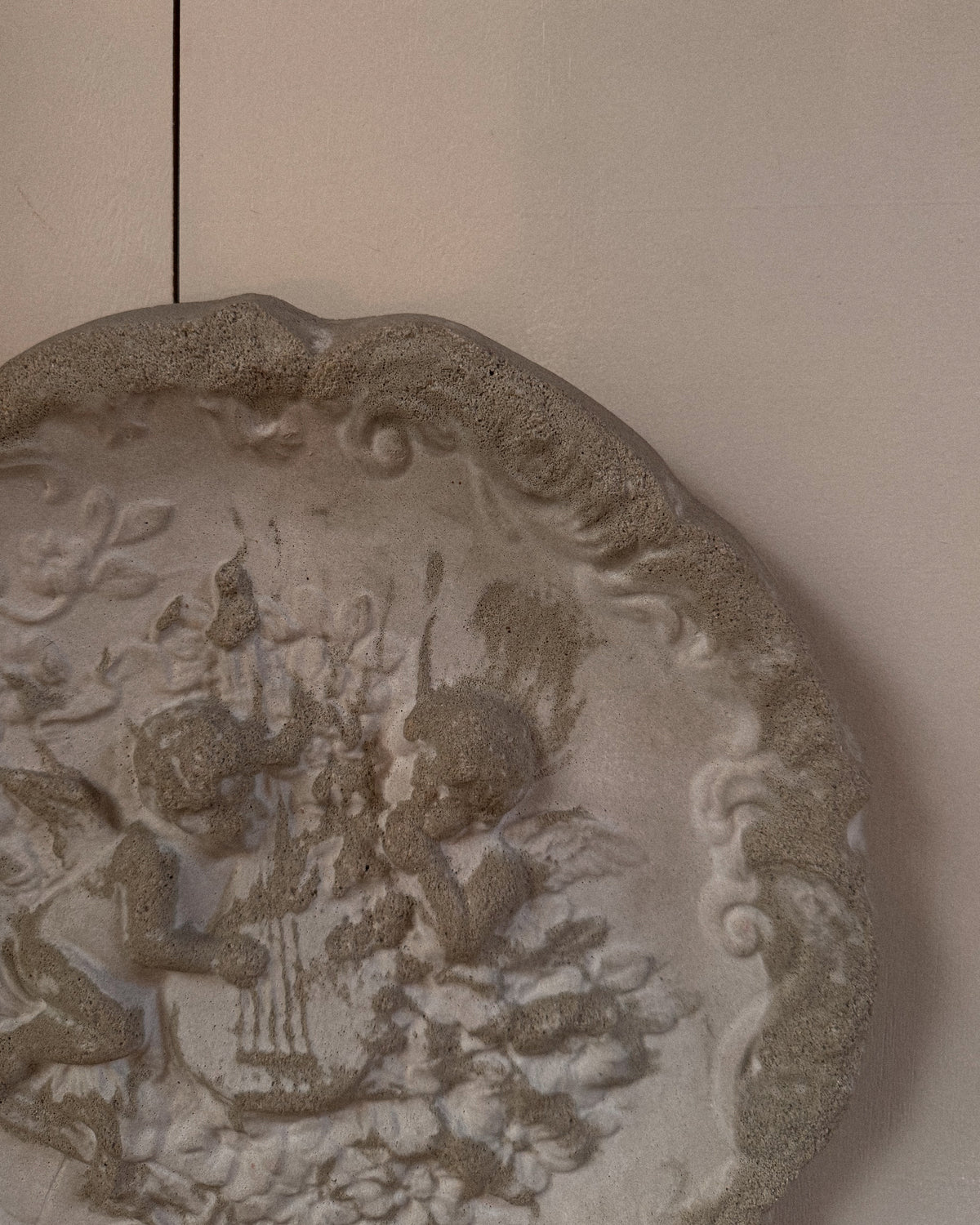 Concrete wall hanging of cherubs playing a lyre harp
